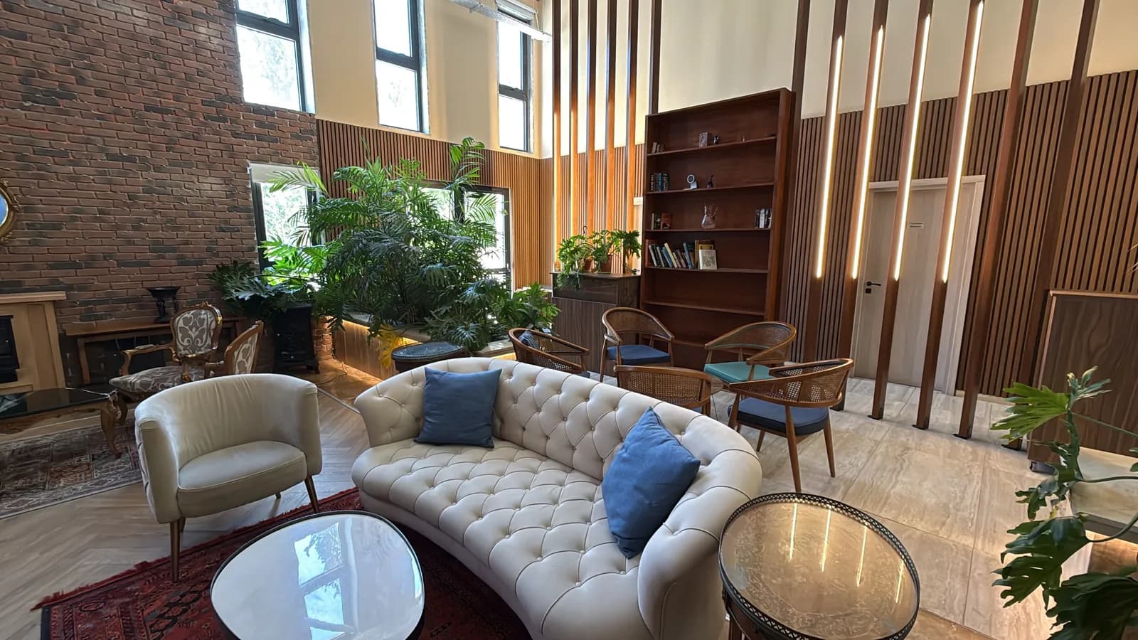 A tufted sofa beside the brick wall and greenery